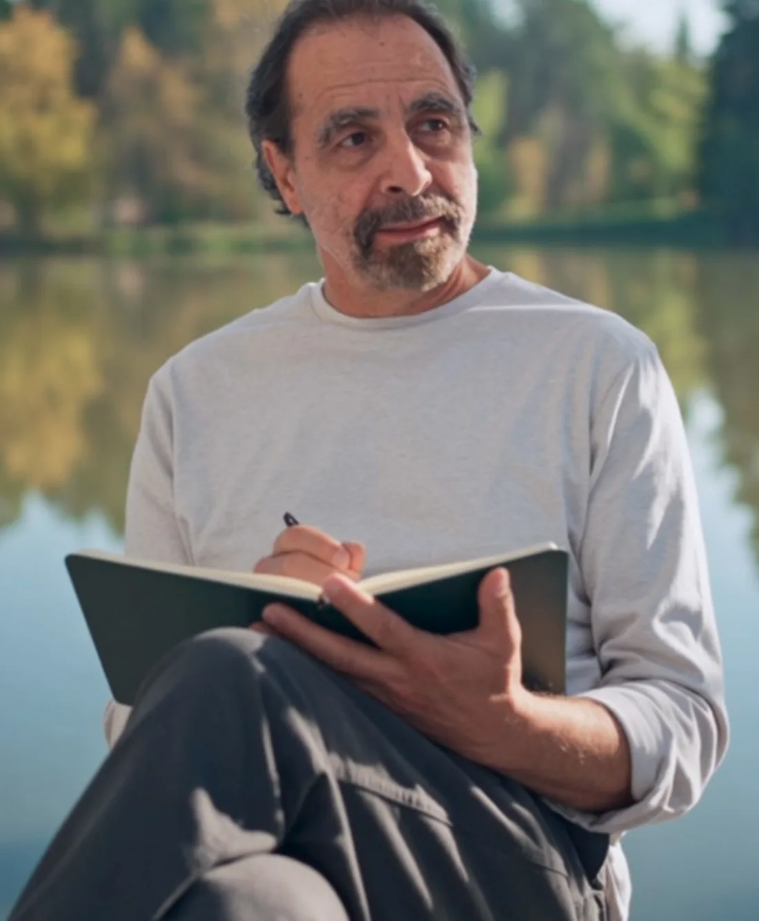 Juan Pablo Ochoa writing by a lake